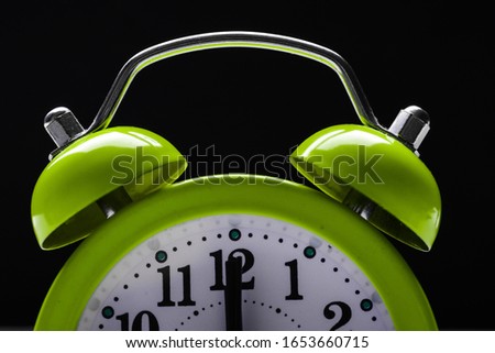 Green retro alarm clock showing differnt times