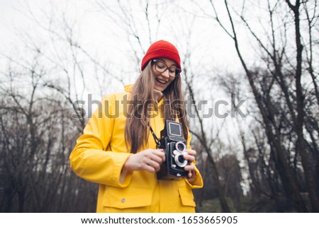 Woman photographer in yellow raincoat with vintage medium format camera