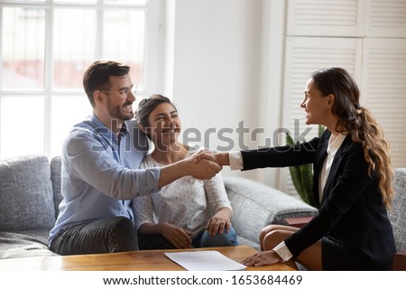 Female realtor or landlord shake hands with multiracial couple real-estate buyers make deal sign rental agreement or sale purchase contract, agent and happy clients renters, buying first home concept Royalty-Free Stock Photo #1653684469