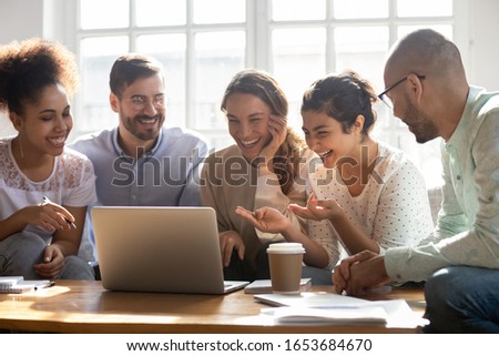 Multi-ethnic five laughing buddies sit on couch indoors watching on computer comedy movie enjoy free time with best friends on weekend, multiracial mates make video call distant communication concept Royalty-Free Stock Photo #1653684670