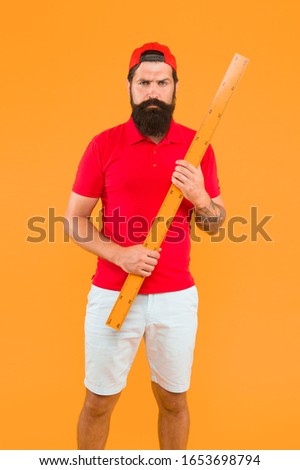 brutal service worker with ruler. measure the length. Measuring a line. back to school. Teacher hold metric ruler yellow background. bearded man preparing for maths and geometry lesson.