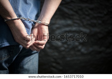 Arrested man in handcuffs with handcuffed hands behind back