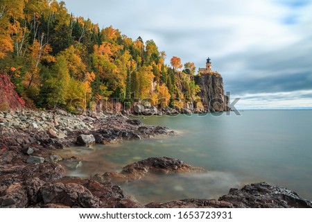 Long exposure of Split Rock Lighthouse complemented with fall colored trees and Lake Superior Royalty-Free Stock Photo #1653723931