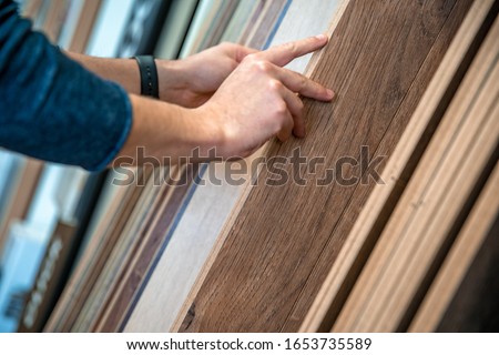 Male selects wooden floor of the sample in the specialized trade Royalty-Free Stock Photo #1653735589