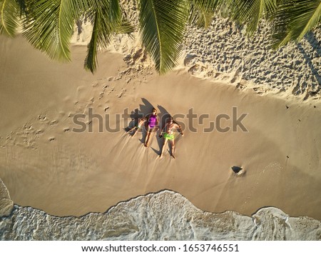 Family lying down on beach aerial top view drone shot at Seychelles, Mahe