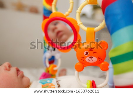 Baby sees his reflection in toy mirror on play mat. toys for newborns and beginners to crawl