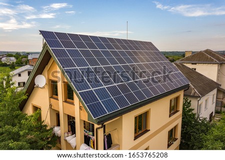Aerial top view of new modern residential house cottage with blue shiny solar photo voltaic panels system on roof. Renewable ecological green energy production concept. Royalty-Free Stock Photo #1653765208