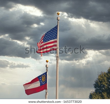 United States and Georgia Flags on poles against blue sky