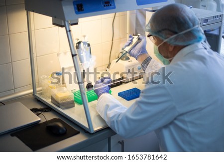 Biologist with protective equipment working on samples in insulation glove uv box in laboratory Royalty-Free Stock Photo #1653781642