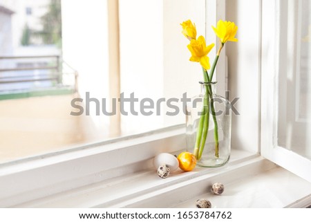 minimalistic easter decoration on windowsill easter bells, daffodils in old building easter eggs on windowsill light background, with copy space
