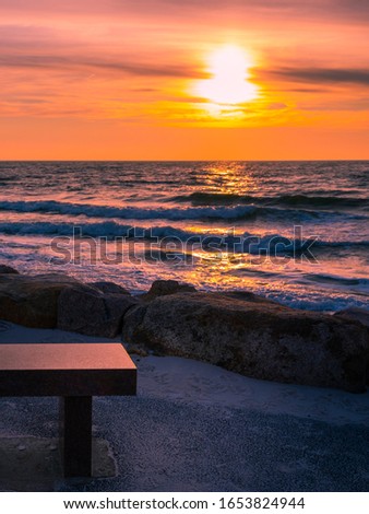 Partial view of a stone memorial bench at the beach at sunset