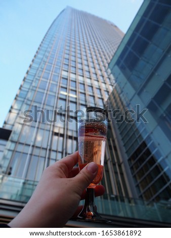 A glass of champagne. A glass is raised to the top against the background of a multi-story building
