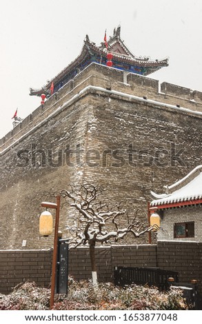 Winter snow scene of the 600 year old Ming Dynasty wall around the city park in Xi'an, China. the sign says "bathroom"