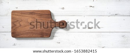 Handmade black walnut wooden cutting board on white desktop.