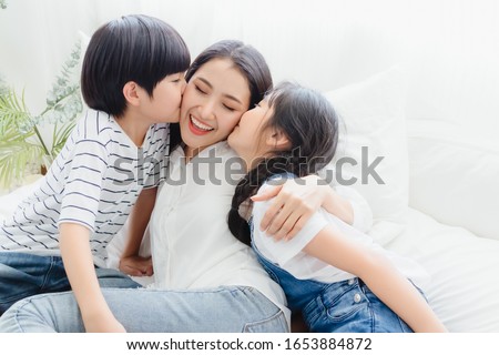 Lovely happy Asian family at cozy home. Son and daughter kiss mother with enjoy ,relax and playful together in bedroom. Happiness relationship and bonding of love between parent and children moment

