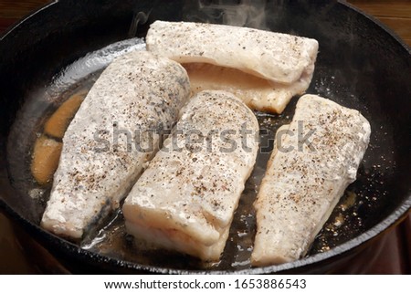 Frying portions of fresh fish in a black cast iron pan