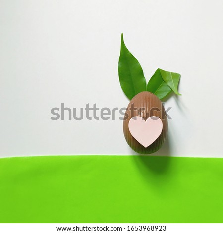 Happy Easter. Minimal Easter concept: chocolate egg and rabbit ears made from fresh leaves