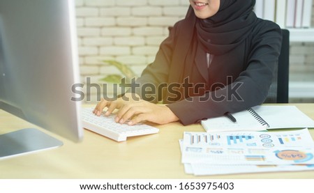 Young beautiful asian muslim business woman wearing black hijab,working at coworking place. Royalty-Free Stock Photo #1653975403