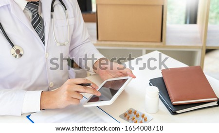 Doctor reading on a document report and writing on paperwork and searching treatment information at office, Medical healthcare concept