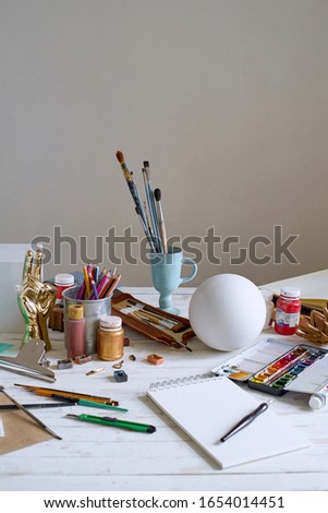 Artist studio with paper and utensils. Workspace of designer illustrator with lots of materilals and equipement.                              