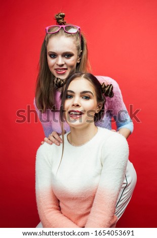 two best friends teenage girls together having fun, posing emotional on red background, lifestyle people concept