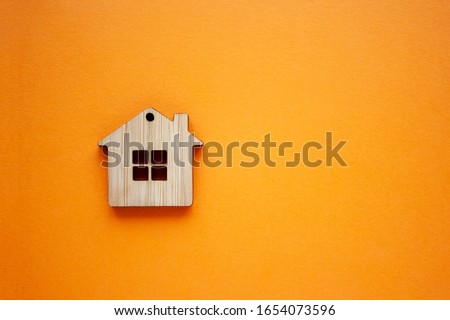 House, insurance and mortgage, buing and rent concept. Small wooden house toy on orange background top view copyspace