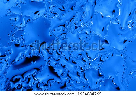 Blue drops of water on glass as an abstract background.