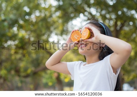photo Happy Little asian girl child standing showing front teeth with big smile. Covering eyes with orange.
fresh healthy green bio background with abstract blurred foliage and bright summer sunlight.