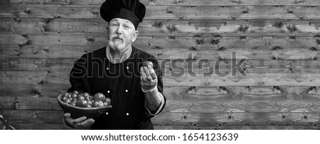 Farmer in uniform with fresh vegetables on a wooden bacground