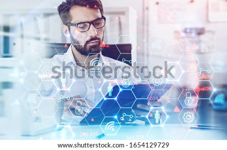 Confident bearded businessman in glasses reading contract in blurry office with double exposure of futuristic digital interface. Concept of technology in business. Toned image
