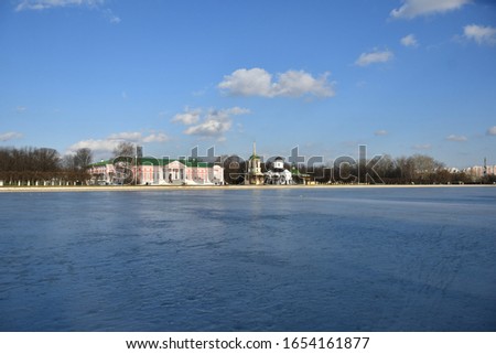 Building in Moscow park. White window on the wall of an old building Kuskovo. Frozen pond in front of the park. blue sky. ice blue. Gray clock building in Moscow park. pink building wall. the wall of 