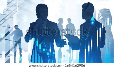 Partnership and stock market concept. Silhouettes of business people in city with double exposure of blurry digital graph. Toned image