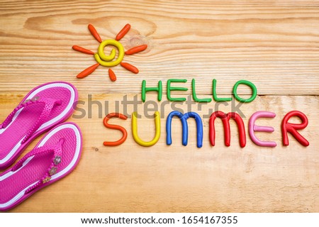inscription "hello summer" made from plasticine of different colors on a wooden surface
