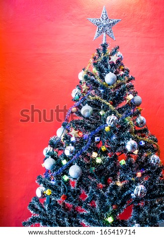 Decorated christmas tree on red wall background
