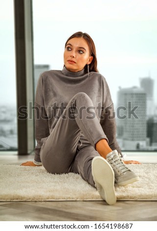 Slim young woman sitting on the floor and big window of city landscape.Free space for your decoration and sunny day. 
