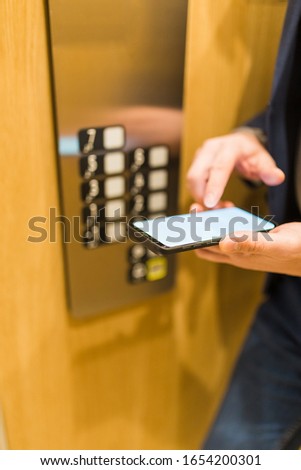 Man hands holding blank screen mobile phone in elevator
