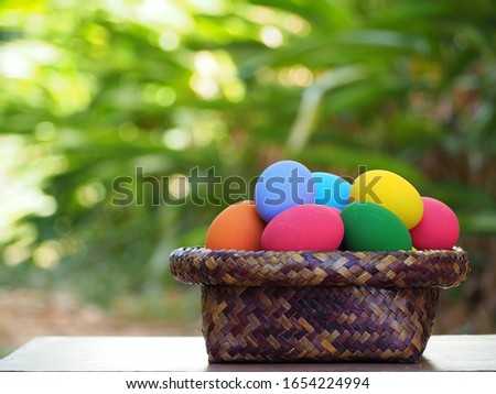 Colorful eggs in a basket on the wood table and nature blur background. Easter fastival.