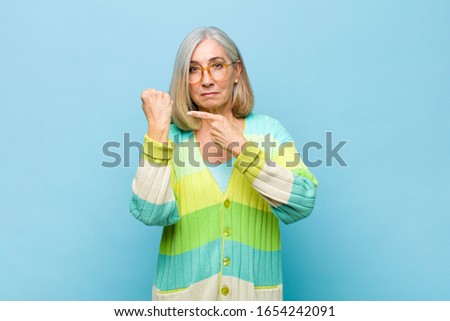 senior or middle age pretty woman looking impatient and angry, pointing at watch, asking for punctuality, wants to be on time