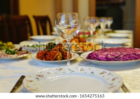 an empty transparent glass goblet standing on a typical Russian holiday table awaiting guests