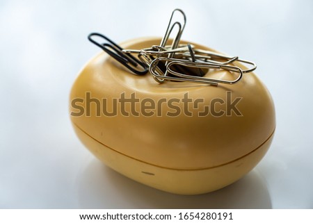 Paper clips in beige plastic oval box on white acrylic background, Close up & Macro shot, Business, Education, Stationery concept