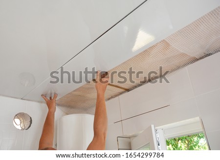 PVC Ceiling Panels, Cladding Installation. Builder installing, renovate, repair white PVC Ceiling Boards in the bathroom Royalty-Free Stock Photo #1654299784