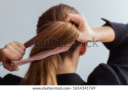 Young woman doing a ponytail with velvet hair tie, scrunchie, view from the back Royalty-Free Stock Photo #1654341769