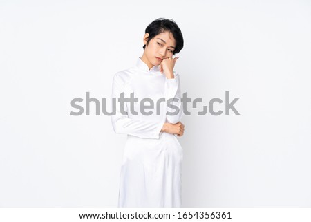 Young Vietnamese woman with short hair wearing a traditional dress over isolated white background with tired and bored expression