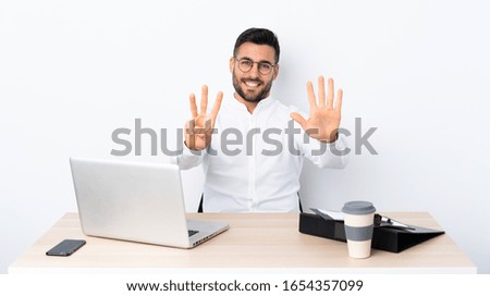 Young businessman in a workplace counting eight with fingers
