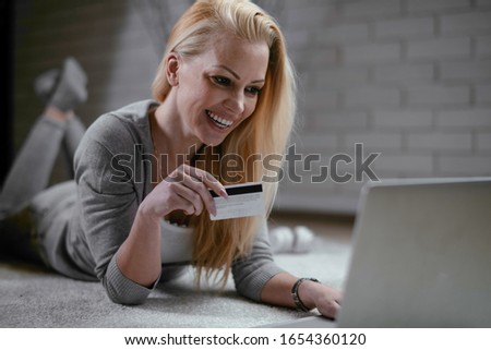 Woman buying online. Beautiful woman lying on floor with laptop and credit card. 
