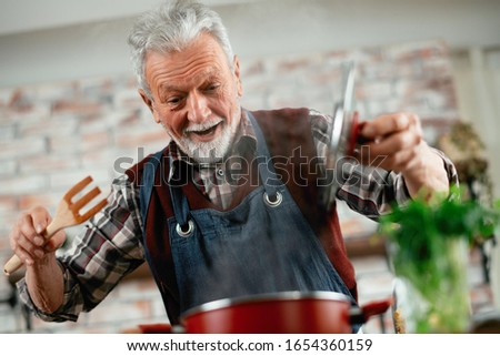 Old man cooking. Senior man in kitchen.  Royalty-Free Stock Photo #1654360159
