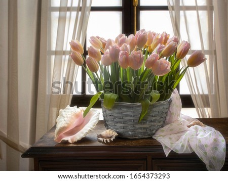 Still life with a basket of pink tulips by the window