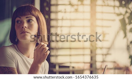 Portrait of attractive smart minded woman holding pen and working