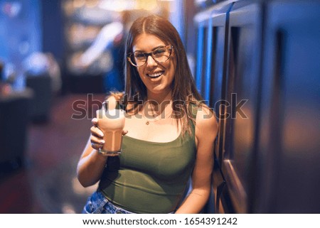 Young beautiful woman smiling happy and confident. Standing with smile on face holding glass of coffee at restaurant