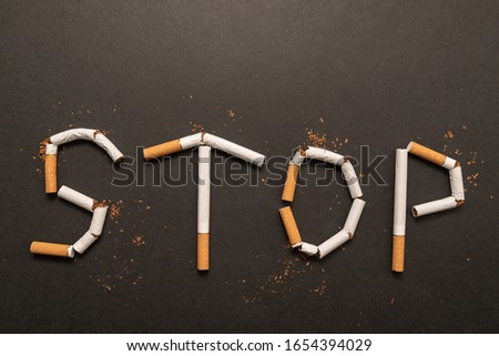 word stop written with cigarettes on black background